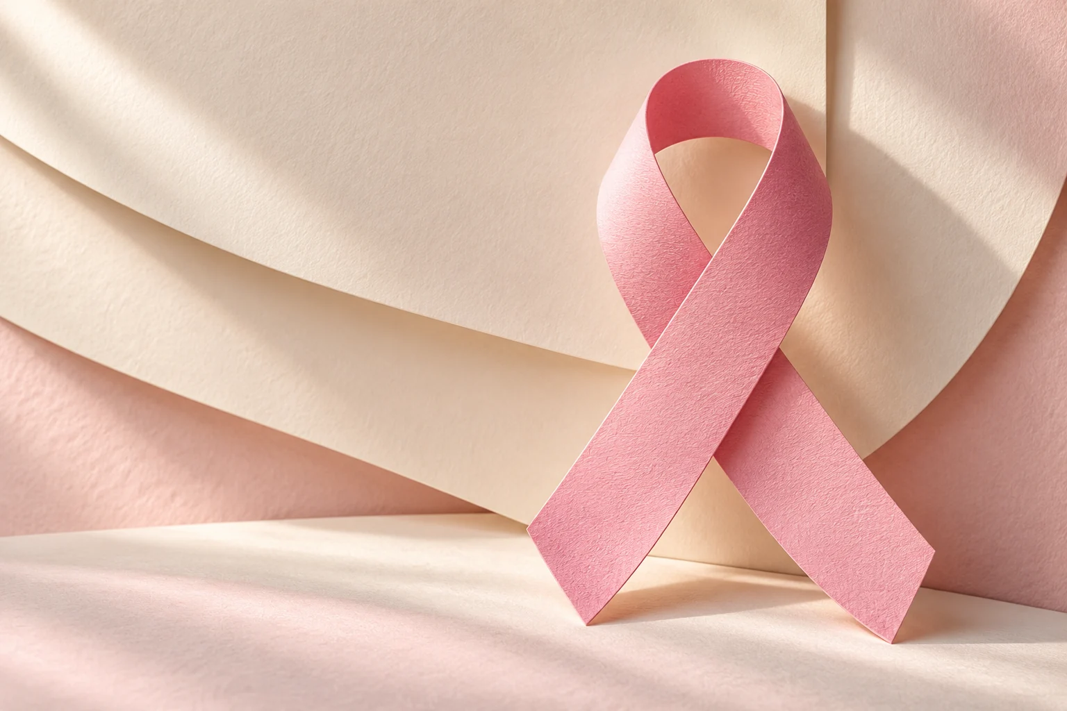 Krem ve açık pembe kâğıt katmanlarının önünde pembe farkındalık kurdelesi